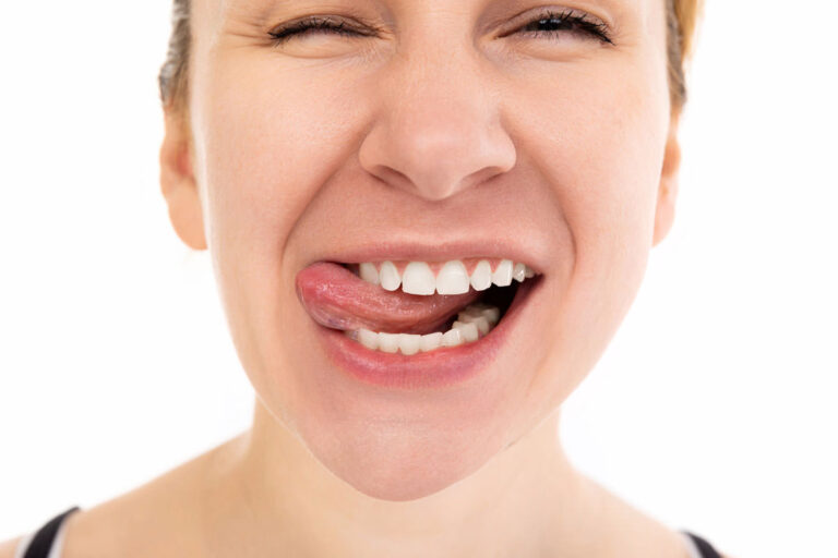 close up portrait of young woman with smile and tongue between teeth squint eyes and cheerful mood
